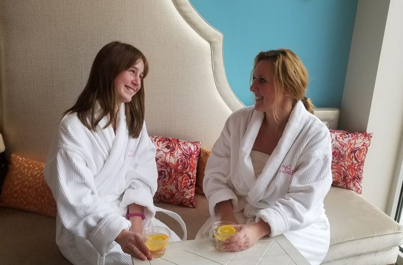 Jennifer and her daughter seated at the spa in robes with fruited water.